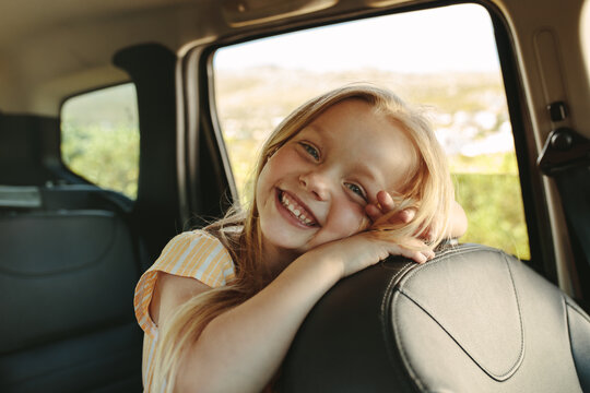Adorable girl sitting in backseat of car
