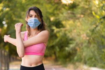 A girl stretching her arm muscles after playing sports with the mask to avoid the Covid virus 19