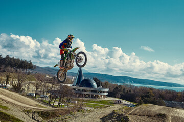 racer on mountain bike participates in motocross race, takes off and jumps on springboard, against the blue sky. Close-up. concept of extreme rest, sports racing.