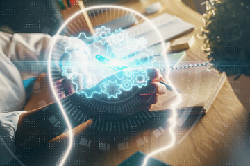 Multi exposure of writing hand on background with brain hologram. Concept of self learning.