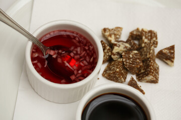 close up top view shot of two white cups with soy sauce and red vinegar mignonette marinade with shallots inside, on a white plate background