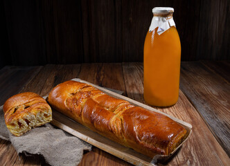 ruddy pie with orange filling, bottle of pumpkin juice, wooden table, rustic style