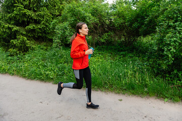 young girl in red jacket runs in the forest 