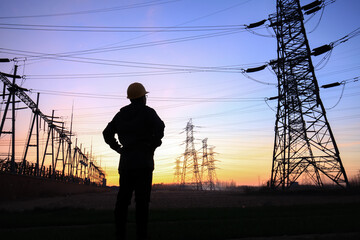 Electricity workers and pylon silhouette, Power workers at work - obrazy, fototapety, plakaty