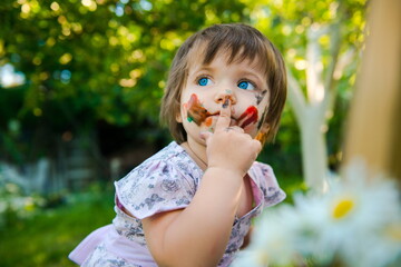 little girl is drawing. Young artist. Painting.  Funny girl in the park. activity for children. funny girl painted her face. Dirty face 