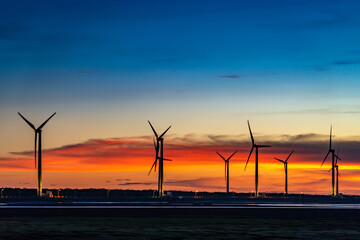 Wind turbines or wind energy converter in sunset time with rosy clouds in background