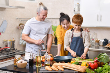 Happy family of mother father and daughter cooking in kitchen making healthy food together feeling fun