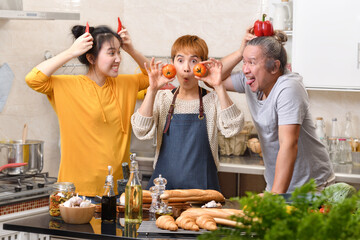 Happy family of mother father and daughter cooking in kitchen making healthy food together feeling fun and making funny faces
