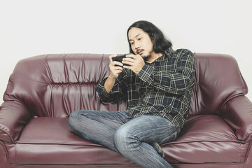 asian men using smartphone while sitting on sofa