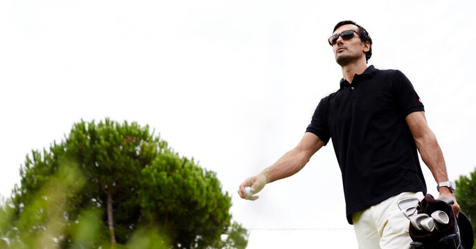 Low Angle Portrait Of Professional Golf Player Walking To The Next Hole Holding Bag For Clubs, Good Golf Game At Summer Evening Weekend On The Course