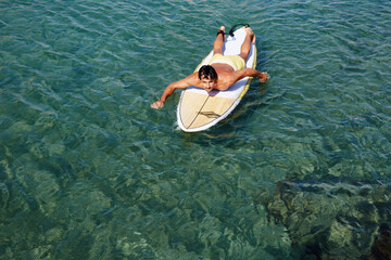 Shot of a handsome young man enjoying a surf in clear blue water, male surfer in the ocean water with surf board, sexy man surfing at the beach, men drifting on surfboard in the copy space ocean