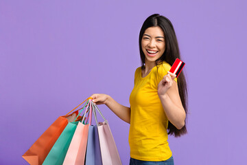 Fototapeta na wymiar Happy Shopaholic. Joyful Asian Girl With Colorful Shopping Bags And Credit Card