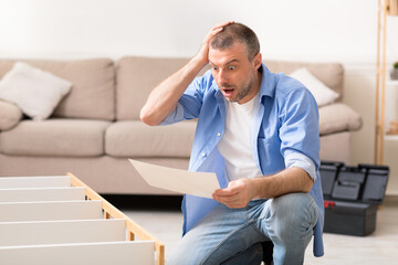 Shocked Man Looking At Shelf Installation Instruction Scratching Head Indoors