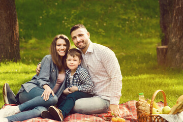 Happy family with cute child enjoying their time on picnic in park, blank space