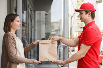 Modern delivery service at home. Courier and customer hold on to parcel
