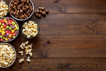 Colorful popcorn in paper box on wooden table top-down copy space