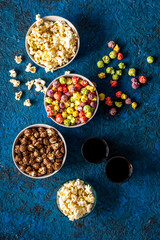 Obraz na płótnie Canvas Set of flavored popcorn and soda on blue desk from above