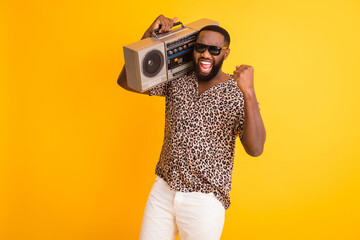 Photo of crazy handsome dark skin guy hold shoulder retro tape recorder raise fist cool holidays...