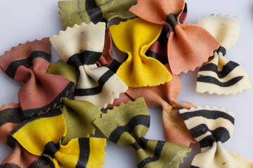 filled frame close up top view flat lay background wallpaper shot of a bunch of colorful multi color raw Italian farfalle bow pasta on a white background