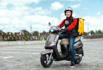 Fototapeta na wymiar Courier Guy Delivering Meals In Box, Posing On Motorbike Outdoors