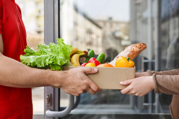 Delivery from supermarket. Courier hands over box of food