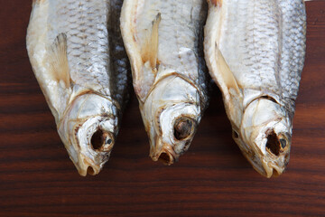 detailed close up top view shot of three Russian dried salted vobla (Caspian Roach) fish on a dark wooden plate background