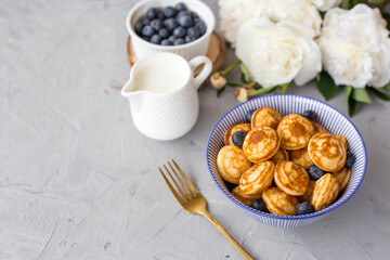 Mini cereal pancakes with blueberries in a bowl on gray background. Trendy food concept, Breakfast time for kids. Menu, recipe, top view or flat lay