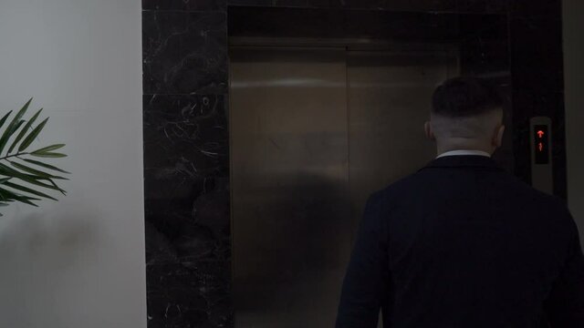 Mature businessman leaves a hotel room walks along the corridor of the hotel to the elevator