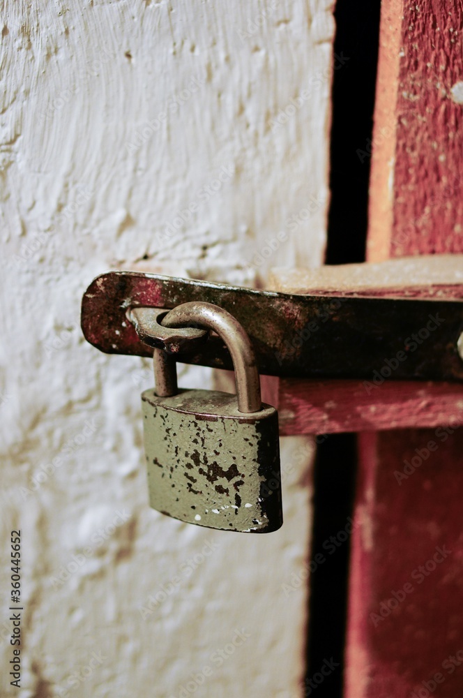 Canvas Prints Vertical shot of an old rusty lock on a red door in a white wall background