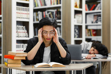 Two tired students studying in the university library