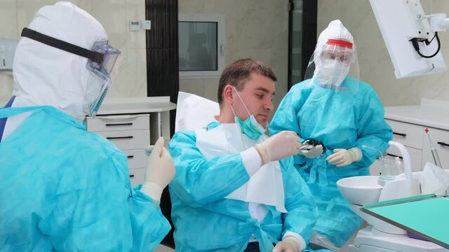 Consultation with a woman dentist. The doctor suggests that the patient disinfect the mouth with a solution of chlorhexidine. Healthcare and Medicine Concept during coronavirus pandemic.