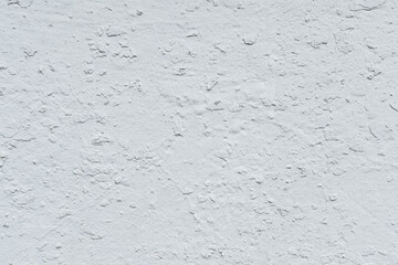 rough texture of a white painted wall with pieces of old paint - background