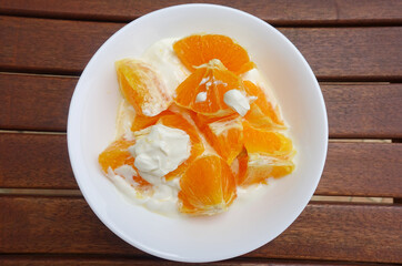 Dietetyczny deser pomarańcze z jogurtem na drewnianym blacie