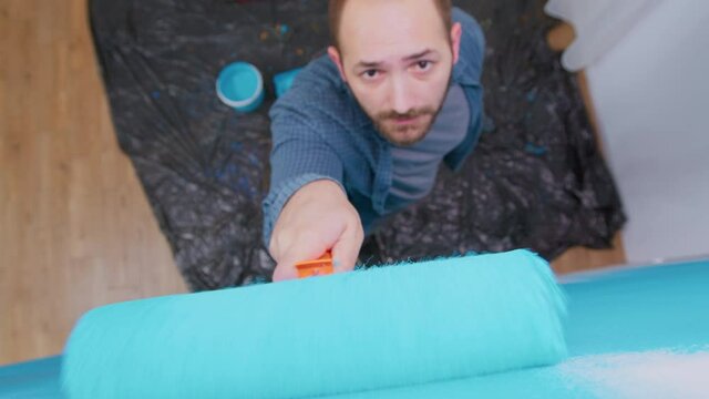 Painting wall with roller brush by handyman during home renovation. Apartment redecoration and home construction while renovating and improving. Repair and decorating.
