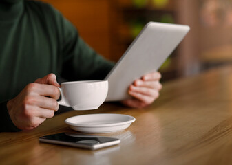 Man hands holding cup of coffee and digital tablet