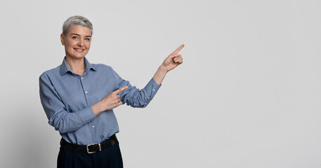 Smiling Middle-Aged Businesswoman Pointing At Copy Space With Two Hands, Recommending Something