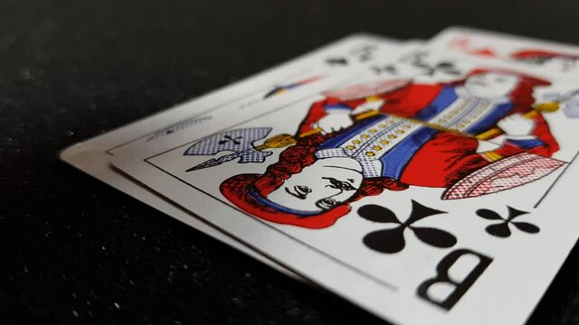 Macro view of cards of jacks falling on a black shiny table one at a time
