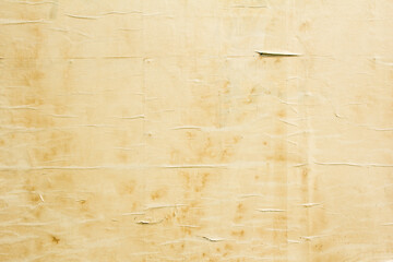 Old crumpled beige brown paper poster with dirty stains on wavy rough surface. Brown weathered...