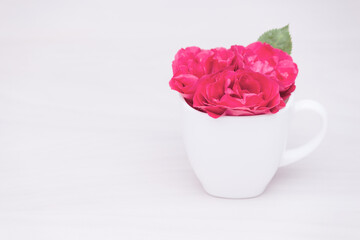 Flowers red roses in a cup on wooden background. Flat lay, top view, floral background, toned.
