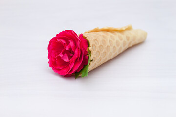 Flowers red roses in a waffle cone on white wooden background. Flat lay, top view, floral background.