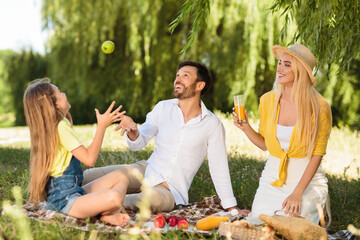 Family Of Three Having Fun Sitting On Blanket In Park