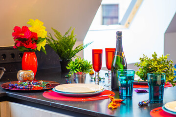 Close-up of the set table. Clean dishes and glasses. Bottle of wine. Decorative flowers. Modern interior.