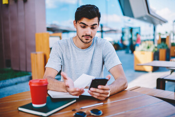 Skeptical male blogger amazed with incoming notification with strange message about interner...