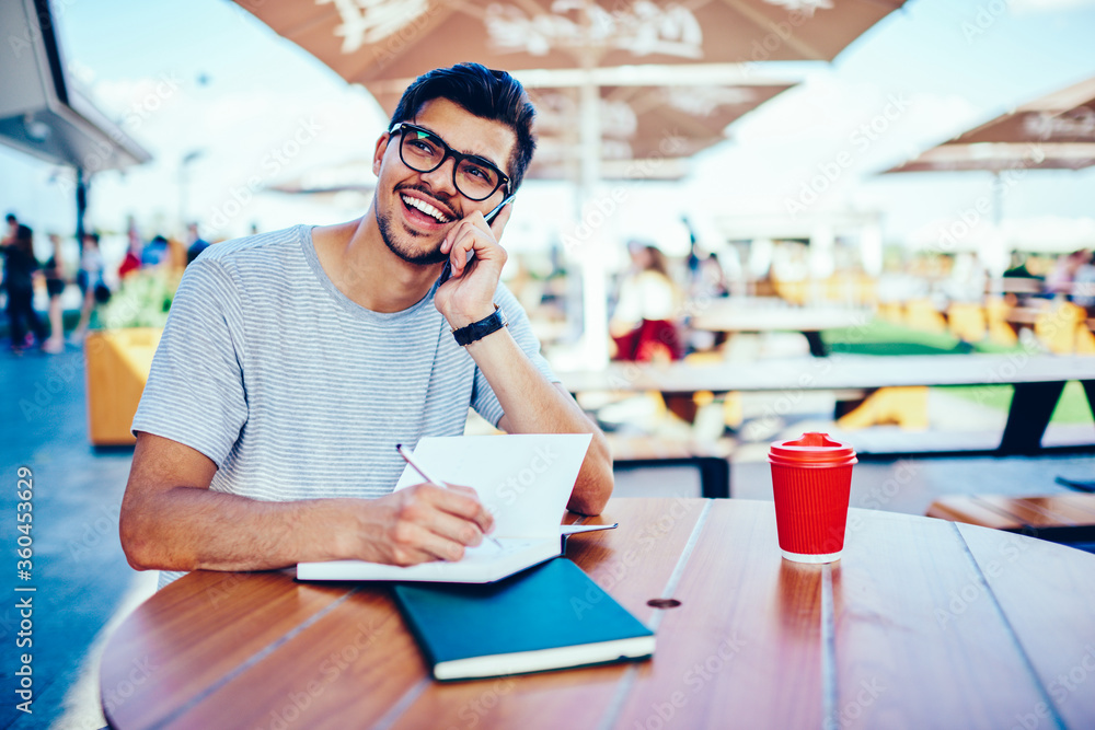 Poster happy student in spectacles laughing during funny conversation with best friend on smartphone while 