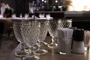 Crystal glasses and plates are served and stand on a wooden table in a restaurant. Background blurred