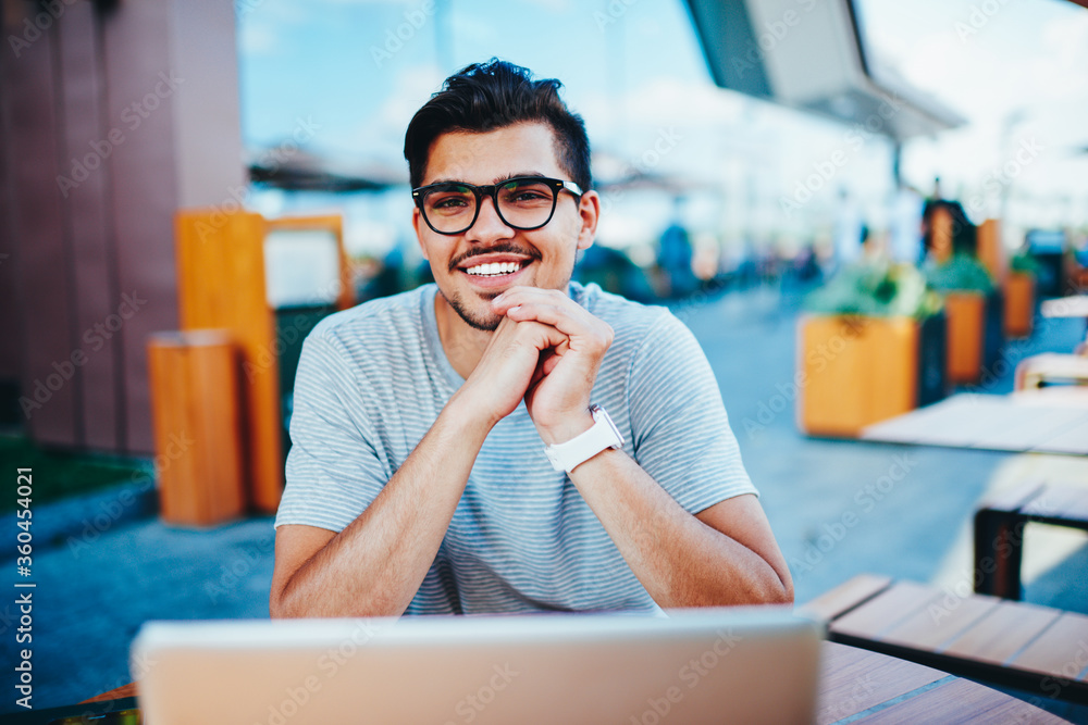 Poster portrait of happy bearded student in optical eyeglasses laughing while smiling at camera during remo