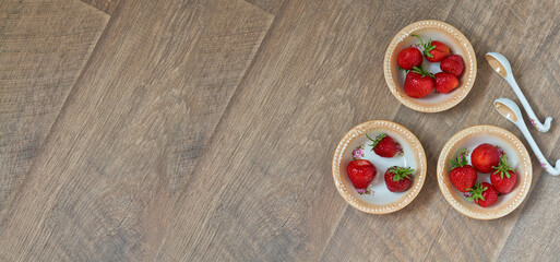 ripe red strawberries in porcelain plates on a wooden brown background