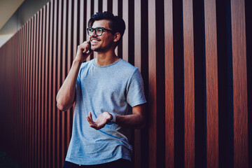 Emotional handsome hipster guy in eyewear discussing ideas during mobile conversation making plans...