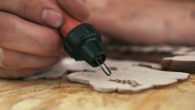 Closeup hand of a craftsman painting an ornament np a wooden board. The technology for the production of handmade souvenirs. Selective focus, shallow depth of field.