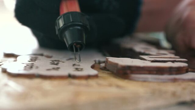 Close-up hand in the glove of a craftsman making wooden souvenirs. Painted wood products